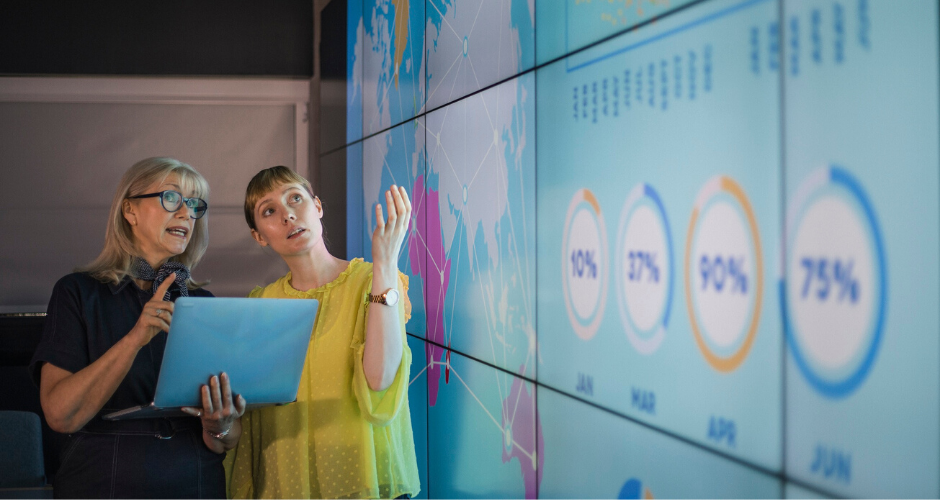 Two women pointing at a  map and data points